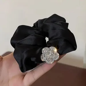 Dettaglio di un elastico in raso nero con ornamento floreale scintillante di strass