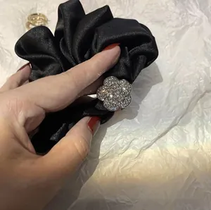Dettaglio dell'elastico in raso nero con fiore di camelia scintillante di diamanti