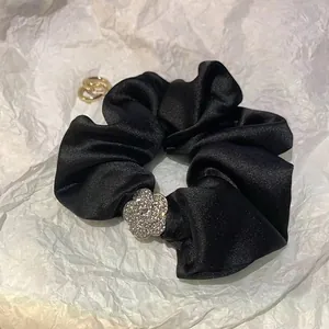 Elegante elastico in raso nero con un dettaglio floreale di camelia in strass argento
