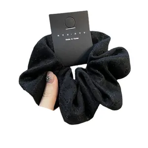 Elegant black lace hair scrunchie with floral pattern on minimalist display card