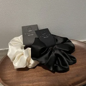 Elegant black and white satin hair scrunchies set on display card in a wooden tray