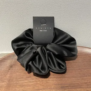 Elegant black satin silk scrunchie on a wooden tray with a minimalist Korean design