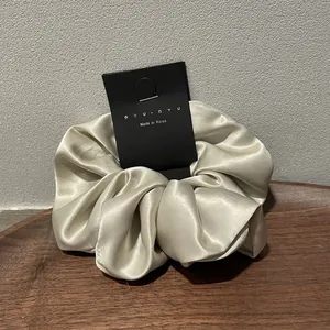 Detail of silk-like satin scrunchie in champagne with premium texture and logo tag