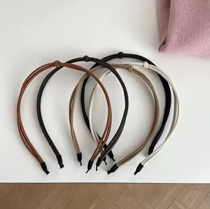 Detail of four thin knotted headbands in brick red, brown, tan and beige synthetic leather
