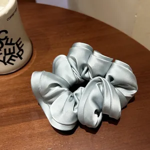 Elegant oversized light blue satin scrunchie with a glossy silk-like finish on wood