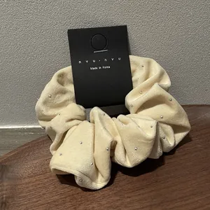 Close-up of cream velvet scrunchie with silver studs on a wooden display tray