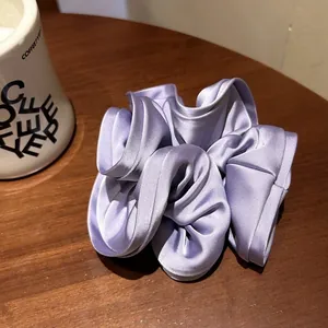 Oversized lavender satin scrunchie with layered ruffle edges on a wooden background