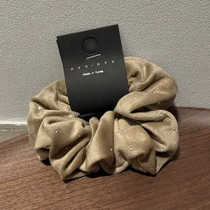 Close-up of beige velvet hair scrunchie with silver studs on a wooden tray