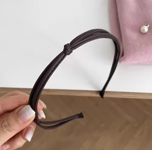Close-up of deep brown synthetic leather triple-strand knotted headband with fine texture