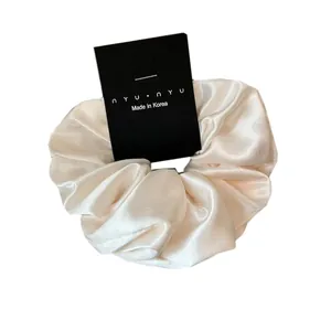 Elegant ivory satin scrunchie with silky shine on display card for hair styling