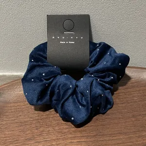 Close-up of a blue velvet scrunchie with rhinestones on a wooden display tray