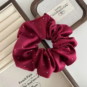 Macro shot of elegant burgundy velvet scrunchie with rhinestones on a jewelry box