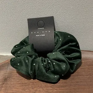 Detailed view of dark green velvet scrunchie with sparkling rhinestones on a card