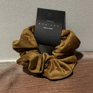 Detail of brown velvet hair scrunchie with silver bead accents on a display card