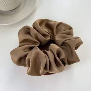 Elegant coffee brown satin scrunchie with silk luster on a minimalist background