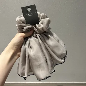 Détail macro d'un chouchou en mousseline gris argenté avec des bords noirs élégants