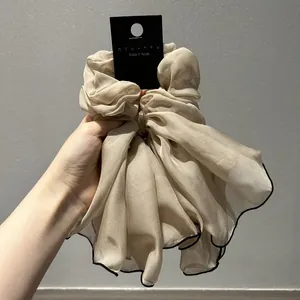Détail du chouchou en organza champagne avec longs rubans et bordure noire