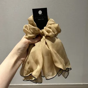 Gros plan sur un chouchou en satin champagne avec bordures noires contrastées