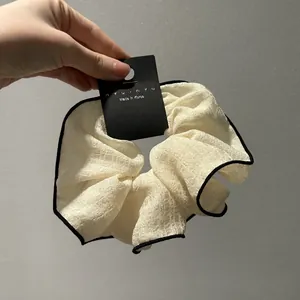 Λεπτομέρεια από κρεμ oversized λαστιχάκι με μαύρο ρέλι και υφή από ελαφρύ ύφασμα