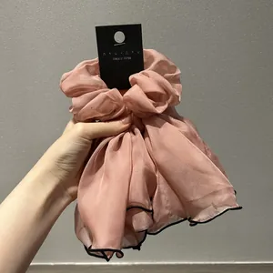 Détail du chouchou en mousseline rose avec bords ondulés noirs et étiquette Corée