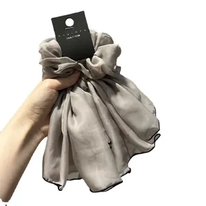 Chouchou élégant en organza gris avec bordure noire sur fond blanc épuré