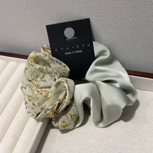 Chouchou patchwork à fleurs et satin en jaune et vert sauge sur un plateau crème