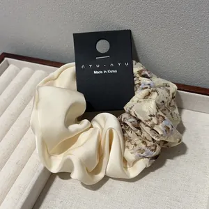 Gros plan détaillé d'un chouchou en satin fleuri sur un plateau à bijoux blanc