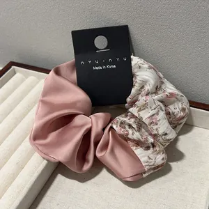 Détail d'un chouchou patchwork floral avec satin rose et tissu imprimé élégant