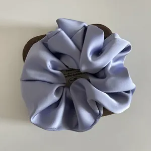 Elegant lavender silk satin scrunchie with French label on wooden display base