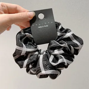 Λεπτομέρεια καρό scrunchie με κυματιστή υφή και ετικέτα σε επίδειξη χειρός
