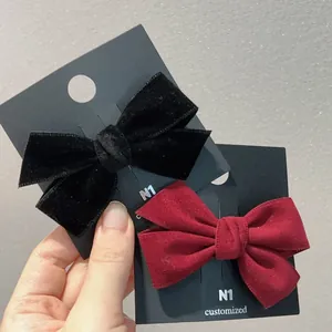 Détails de barrettes à nœuds en velours bordeaux et noir sur une carte de présentation
