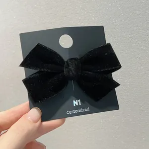 Vue détaillée d'une barrette nœud en velours noir double couche sur sa carte support