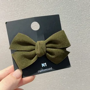 Détail d'une pince à cheveux nœud en velours vert foncé montrant la texture du tissu