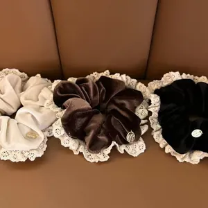 Detailed view of velvet lace scrunchies in cream, brown, and black with metal charms