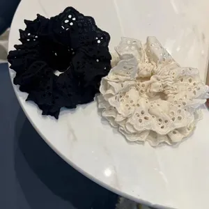 Detailed close-up of ruffled embroidery lace hair scrunchies in black and beige colors