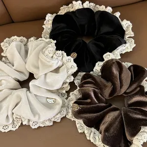 Detailed macro view of velvet hair scrunchies with lace trim and gold metal tags
