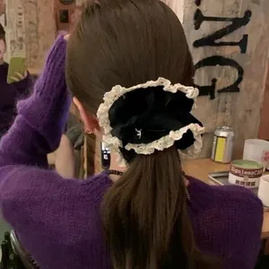 Close-up of vintage black velvet hair scrunchie with lace trim and metal tag on ponytail