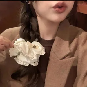 Close-up of a cream satin scrunchie with lace trim and decorative metal bead detail