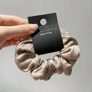 Close-up of beige ribbed fabric hair scrunchie with nyu·nyu retail tag detail