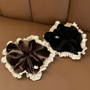 Close-up of velvet scrunchies with lace trim and gold metal tags in black and brown