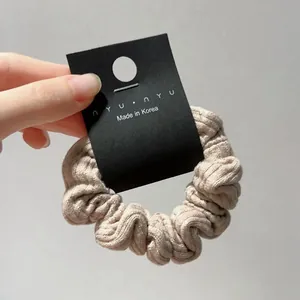 Detail of beige ribbed knit hair scrunchie showing soft texture and premium quality