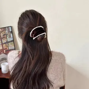 Detail of dark brown velvet scrunchie with pearl trim on woman's brunette hair