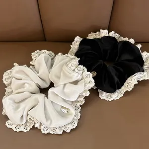 Detailed close-up of velvet scrunchies with lace trim and round metallic brand pendant