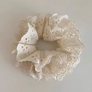 Close-up of ivory lace scrunchie with detailed eyelet embroidery and layered ruffles