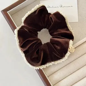 Detailed shot of dark brown velvet scrunchie with lace edges and handmade gold charm