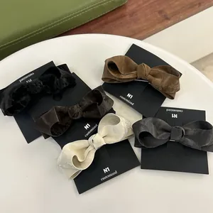 Set of 5 textured leather bow hair clips in black, brown, cream and grey on card