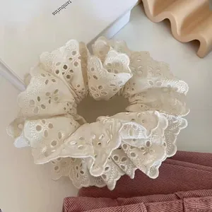 Detail of elegant cream-white embroidered lace scrunchie with floral hollow patterns