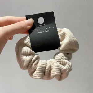 Detail view of beige corduroy scrunchie showing striped texture and soft velvet fabric