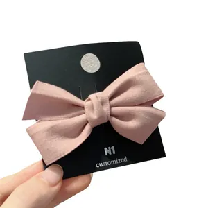 Barrette à cheveux avec nœud en velours rose, texture mate sur carte noire, fond blanc