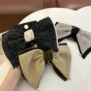 Détail de barrettes à nœud en tweed avec nœud en satin et pendentif cristal élégant